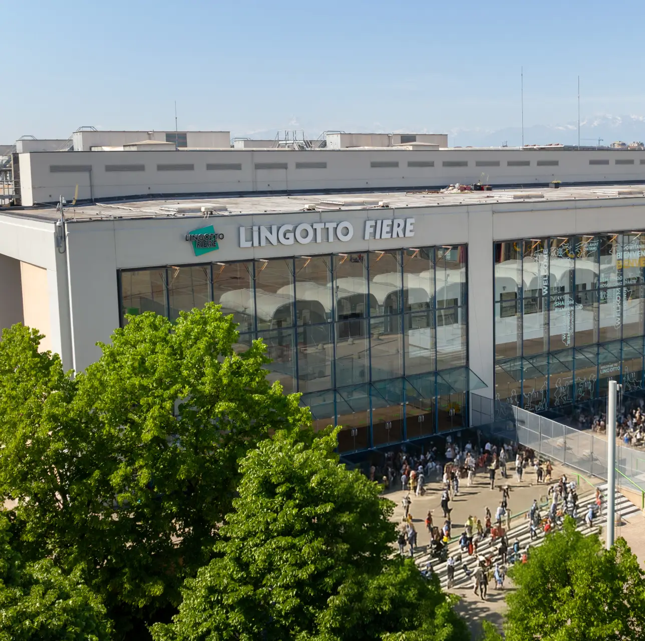 lingotto-fiere Facciata Lingotto Fiere Torino con ampie vetrate, folla in ingresso ed esposizione di luce naturale tra gli alberi.