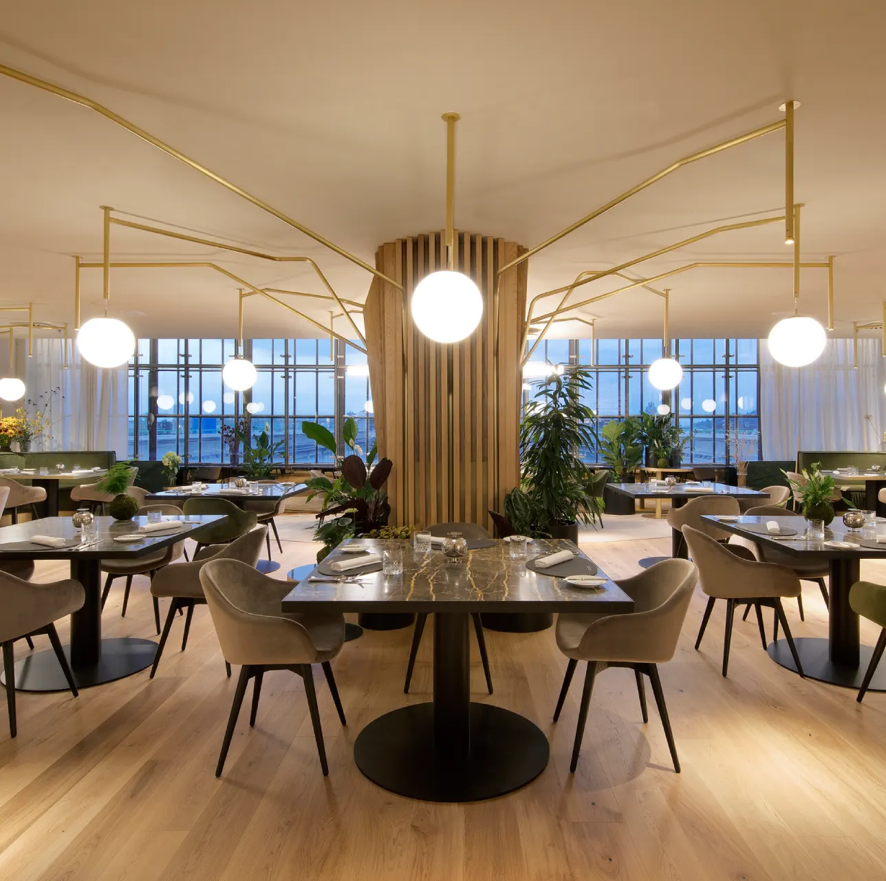 lingotto-la-pista-ristorante Interno elegante di un ristorante panoramico al Lingotto Torino, tavoli moderni, piante e grandi lampade sferiche luminose.