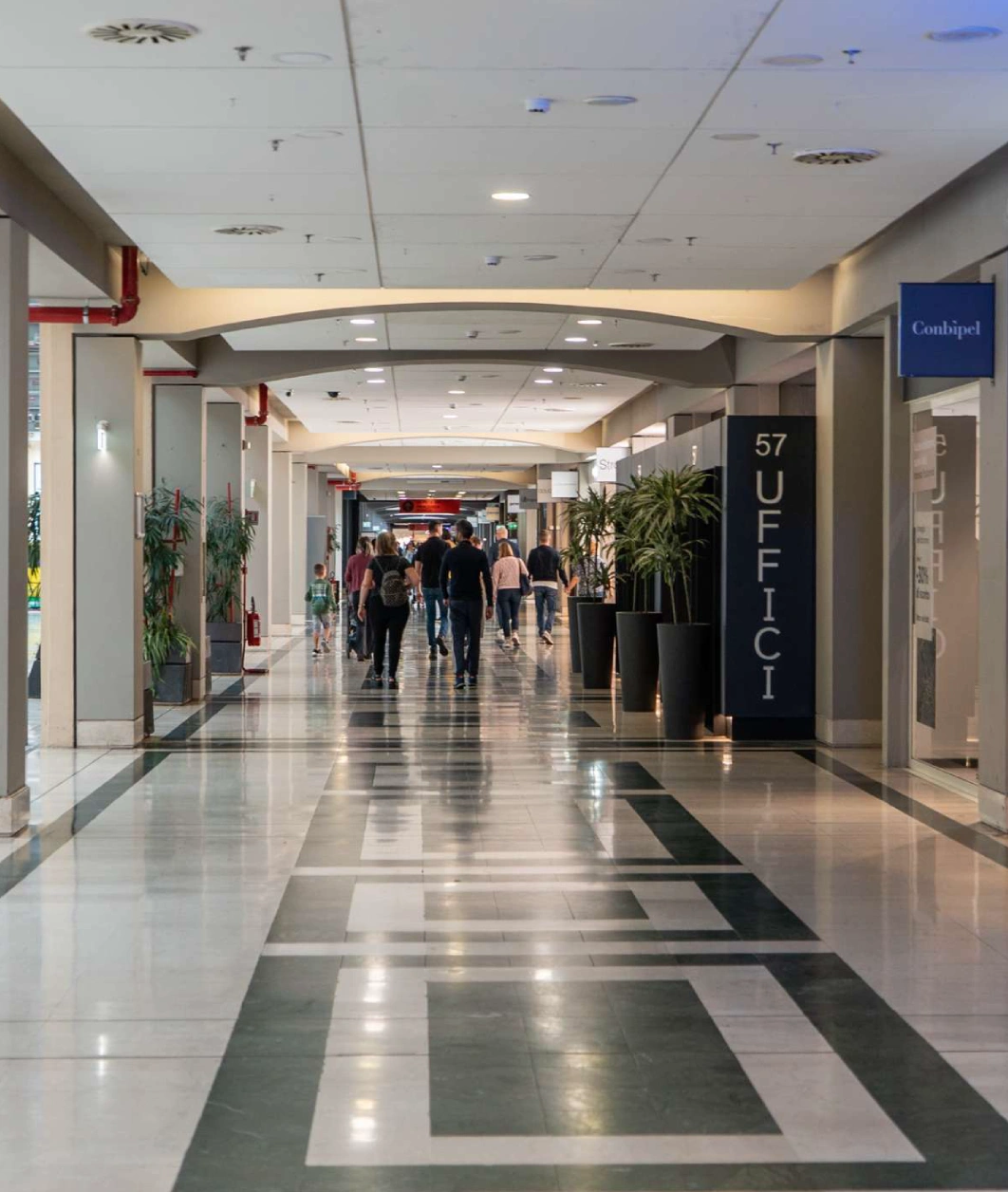 Lungo corridoio interno moderno con persone e uffici